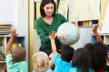 Students raising hands in classroom with teacher