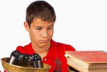 Child looking at videogame controller and at a book